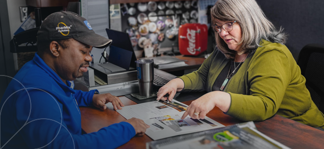 An image of a man and a woman working together and looking at a document.